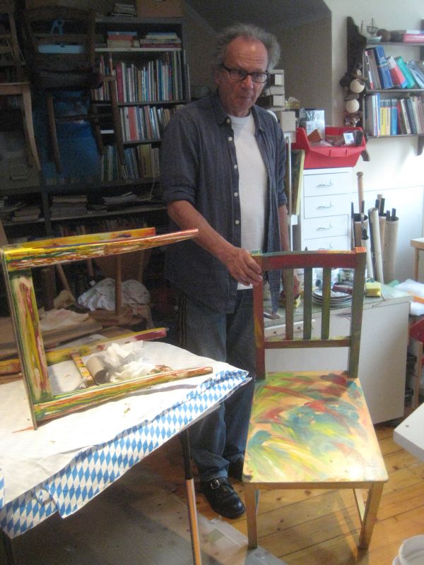 Claus Fettweiss mit einem farbig gestalteten Holzstuhl in seiner Werkstatt