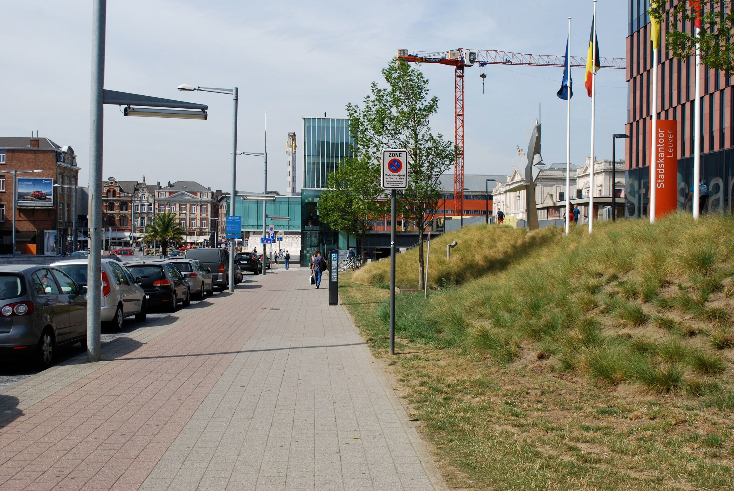 Straße und Gehweg im Umfeld des Bahnhofs von Leuven mit Verkehr und Gebäuden